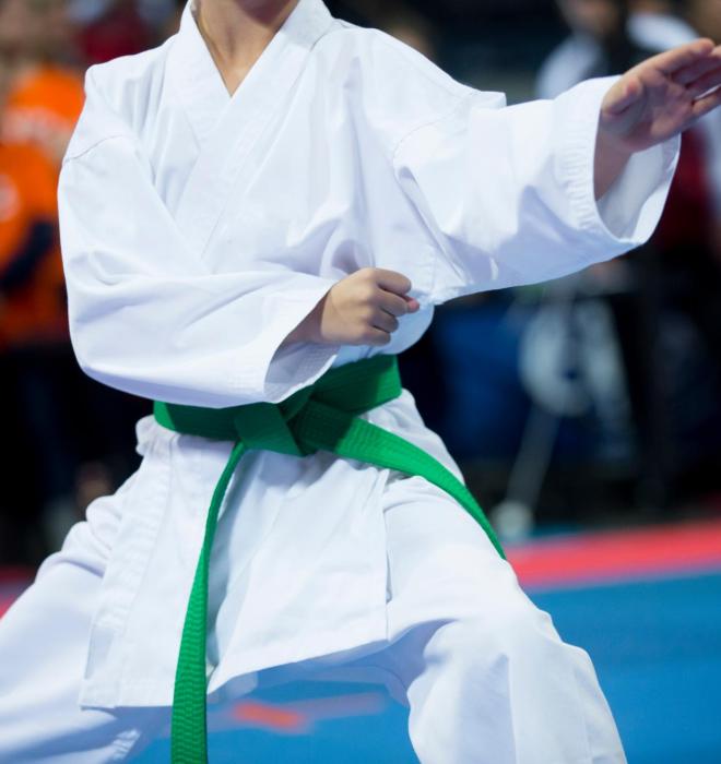 Karateka con cintura verde esegue una mossa in competizione.