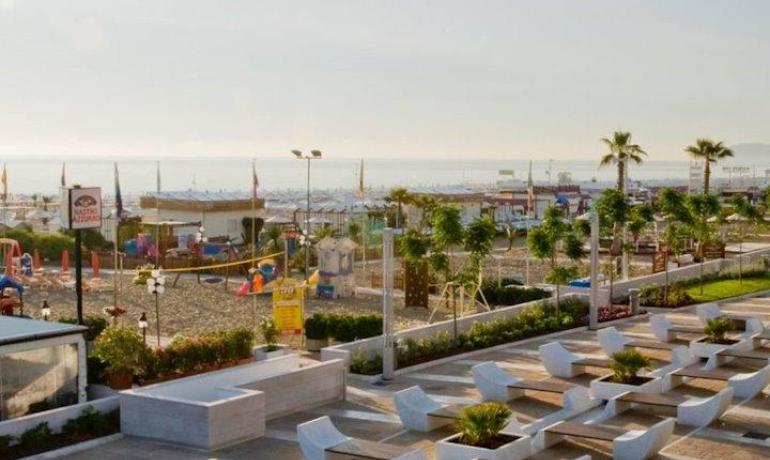 Vista sul mare con panchine moderne e giardino.