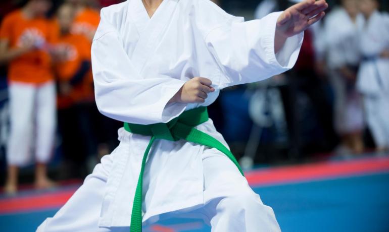 Karateka con cintura verde esegue una mossa in competizione.