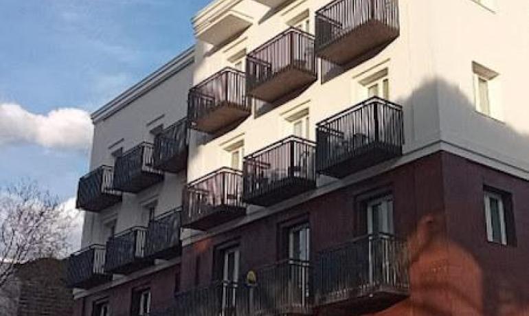 Edificio moderno con balconi, cielo azzurro sullo sfondo.