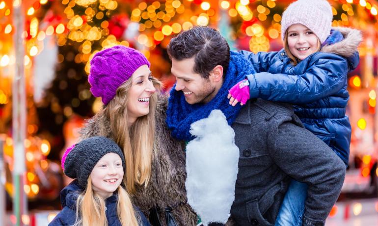 Famiglia felice al mercatino di Natale con zucchero filato.