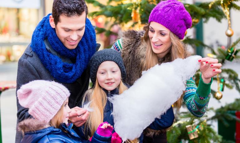 Famiglia felice con zucchero filato davanti all'albero di Natale.