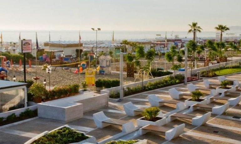 Vista sul lungomare con panchine moderne e spiaggia.