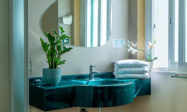 Bagno moderno con lavandino verde e piante.