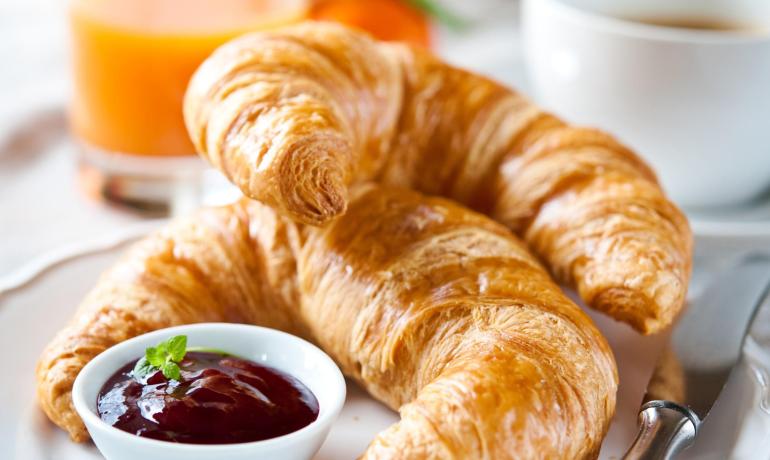 Croissant con marmellata e succo d'arancia su un piatto.