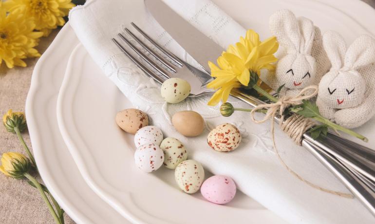 Tavola decorata con fiori, uova e coniglietti per Pasqua.