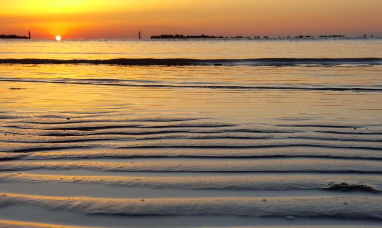 Tramonto dorato riflesso su onde del mare calme.