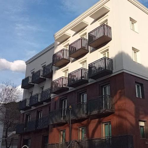 Edificio moderno con balconi scuri e facciata bicolore, cielo sereno sullo sfondo.